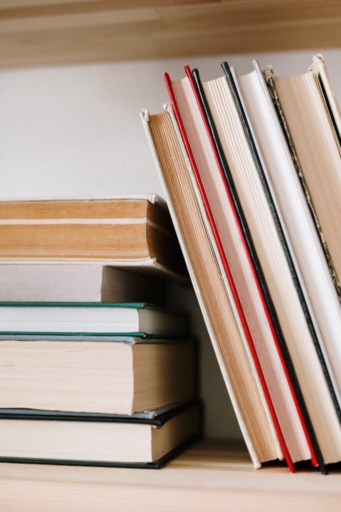 pexels photo 4690297 Close-up of assorted books stacked on a wooden bookshelf, symbolizing knowledge and learning.
